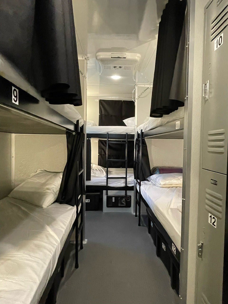 Bunk housing trailer interior with lockers and bedding.