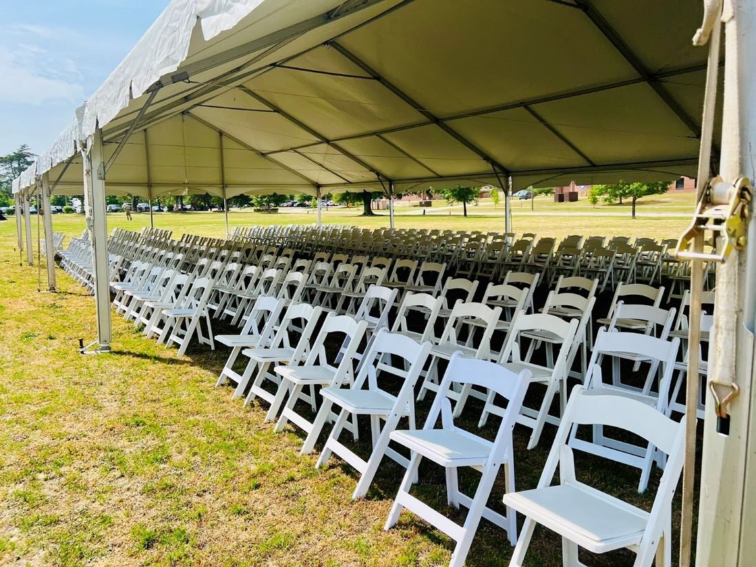 Rows of chairs set up under a tent for a military ceremony.