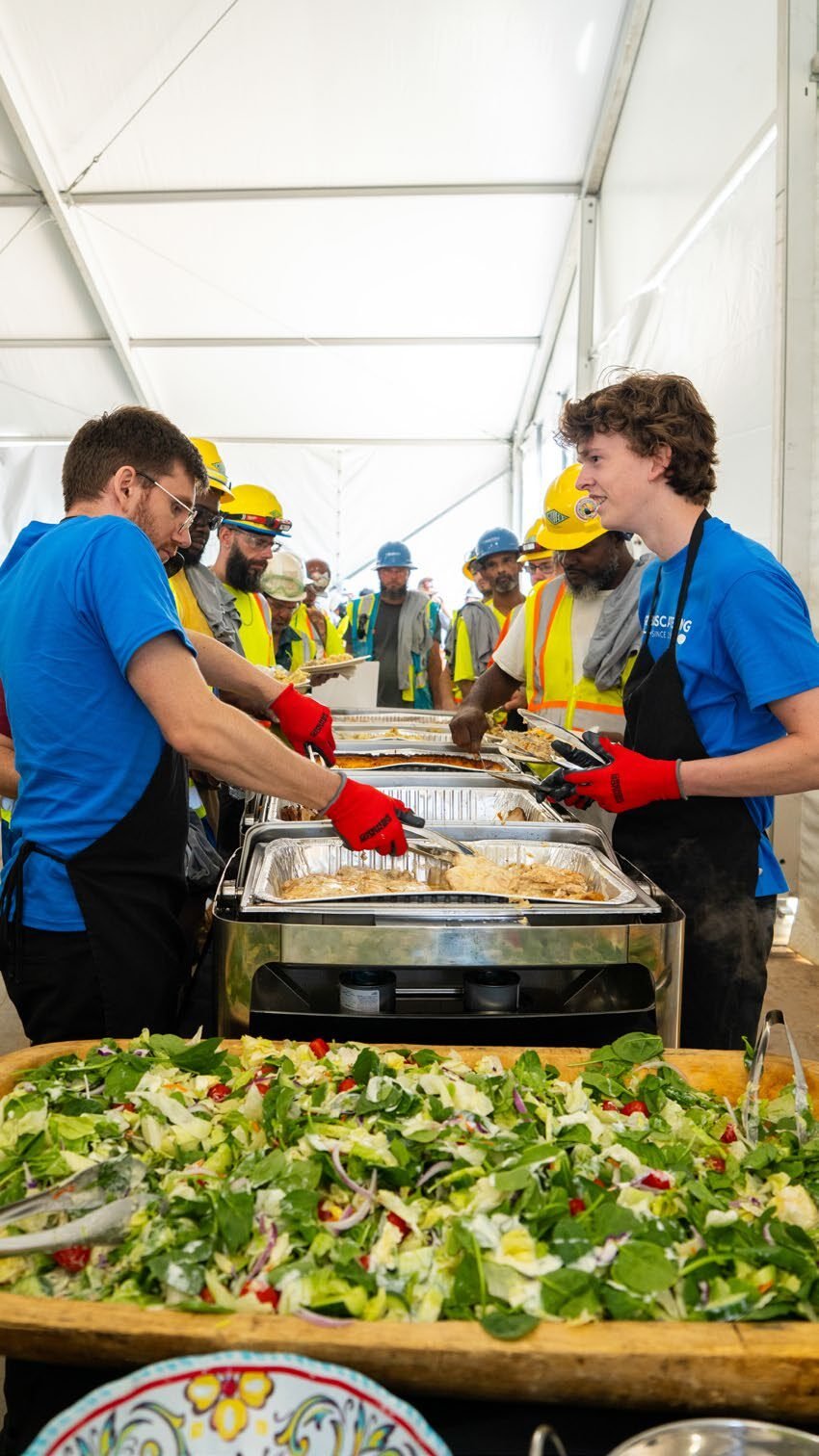 Construction workforce dining under a large support tent at a mega-project jobsite.