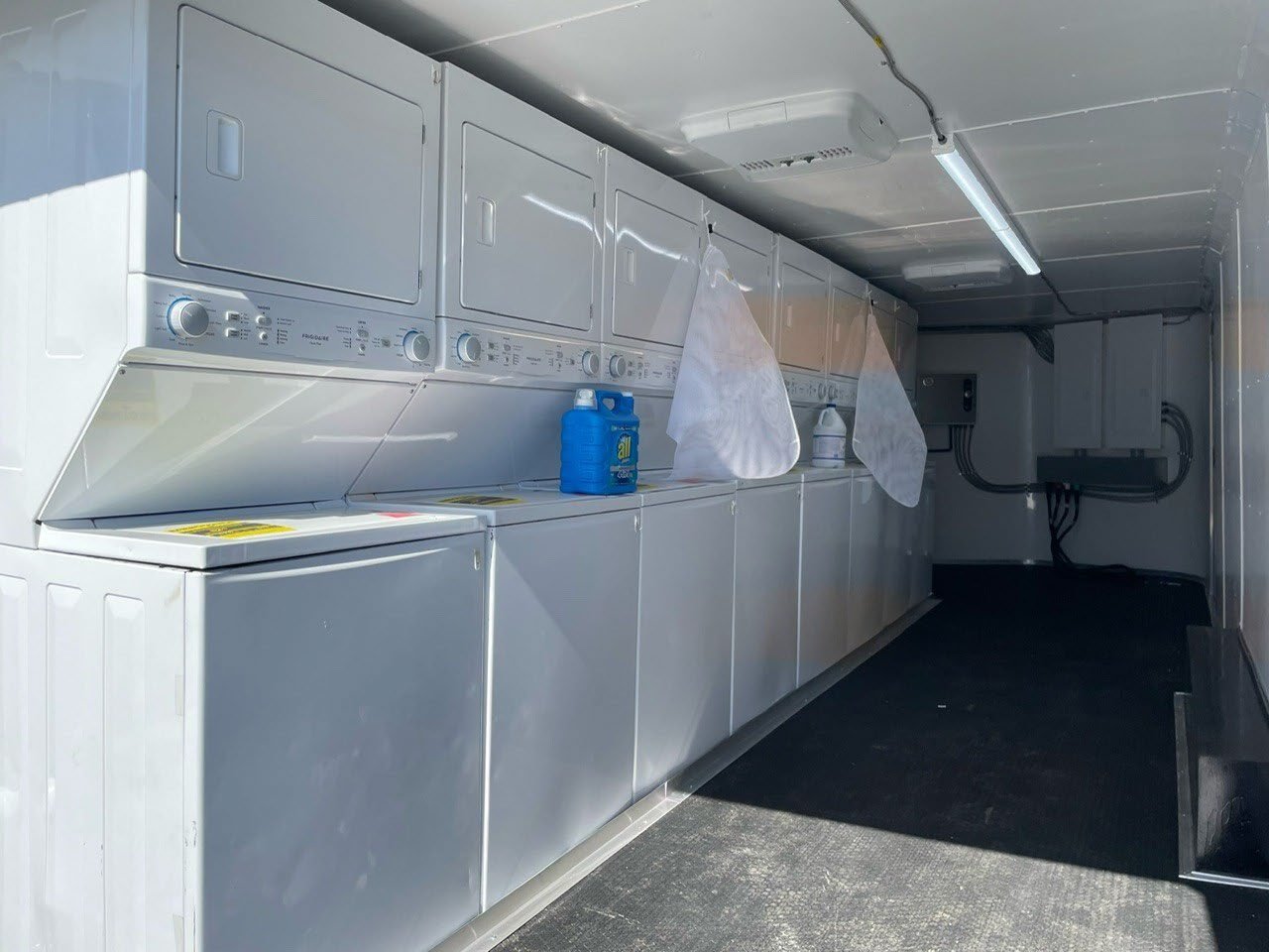 Commercial washer and dryer units inside a laundry service trailer.